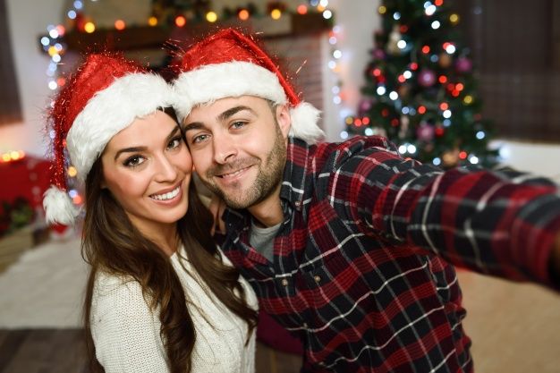 couple-wearing-santa-hat-making-selfie_23-2147578339